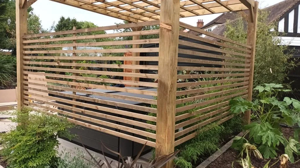 Slatted timber screening with a bench, used as a privacy screen between garden sections