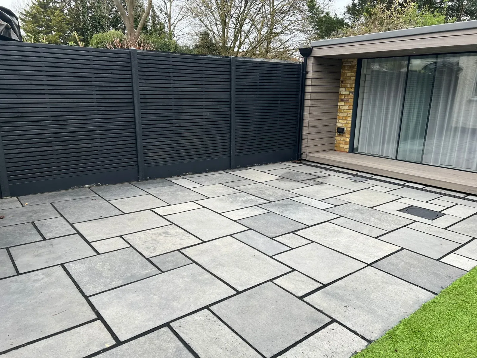 Stone-paved courtyard with new dark slatted fencing fronting the rear extension
